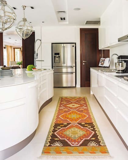 En esta cocina del arquitecto Alejandro Apa, la alfombra (Mihran) y las lámparas (Landmark) suman exotismo y color a una apuesta de muebles (De Otro Tiempo) bien minimalista