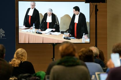 En esta foto de archivo del 16 de diciembre de 2023, periodistas miran una pantalla en la sala de prensa del Vaticano en la que el presidente del tribunal, Giuseppe Pignatone, lee el veredicto del juicio al cardenal Angelo Becciu