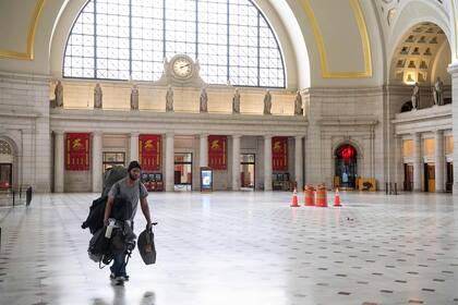 En esta foto de archivo del 22 de mayo de 2020, un hombre lleva sus valijas por el vestíbulo principal de Union Station en Washington, DC