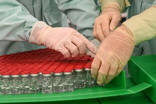 En esta foto de archivo tomada el 11 de septiembre de 2020, los técnicos de laboratorio manipulan los viales tapados como parte de las pruebas de llenado y envasado para la producción y suministro a gran escala de la vacuna contra el coronavirus de la Universidad de Oxford