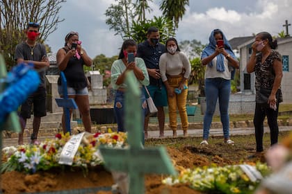En esta foto de archivo tomada el 13 de enero de 2021, familiares de una víctima del Covid-19 asisten al funeral en el cementerio de Nossa Senhora Aparecida en Manaus