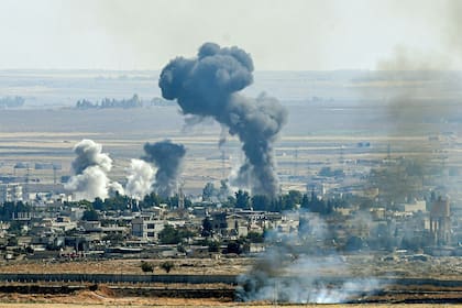 En esta foto de archivo tomada el 14 de octubre de 2019, desde el lado turco de la frontera en el distrito de Ceylanpinar en Sanliurfa, sale humo de la ciudad siria de Ras al-Ain en el sexto día de la operación militar de Turquía contra las fuerzas kurdas