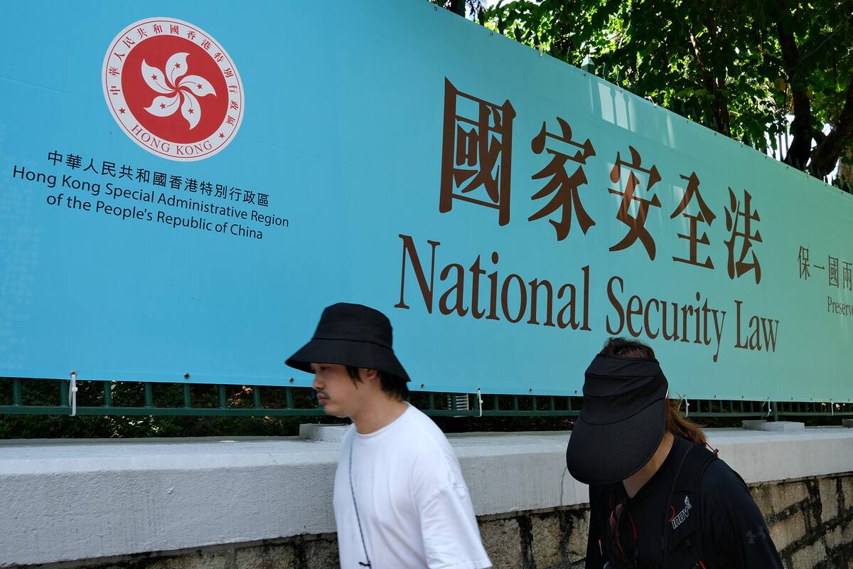 En esta foto de archivo tomada el 15 de julio de 2020, los peatones pasan junto a un cartel del gobierno para la Ley de Seguridad Nacional en Hong Kong