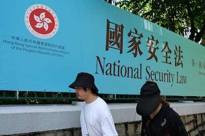 En esta foto de archivo tomada el 15 de julio de 2020, los peatones pasan junto a un cartel del gobierno para la Ley de Seguridad Nacional en Hong Kong