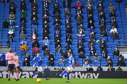 En esta foto de archivo tomada el 20 de diciembre de 2020, los fanáticos, con máscaras debido a la pandemia de coronavirus, se sientan socialmente distanciados durante el partido de fútbol de la Premier League inglesa