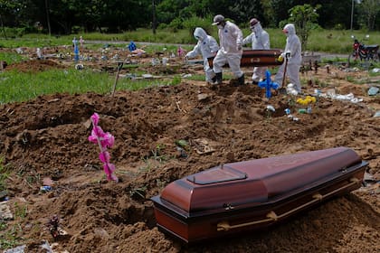 En esta foto de archivo tomada el 20 de marzo de 2021, los trabajadores del cementerio cargan el ataúd de una víctima del Covid-19 antes de enterrarlo en el cementerio público Parque Tapana en Belem, estado de Pará, Brasil