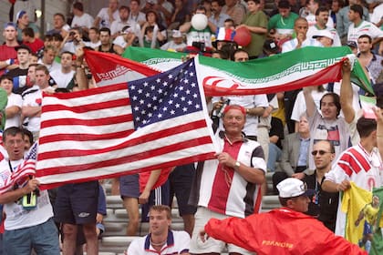 En esta foto de archivo tomada el 21 de junio de 1998, seguidores iraníes y estadounidenses agitan sus banderas nacionales mientras animan a sus equipos durante el partido de fútbol de la Copa del Mundo de Francia 1998