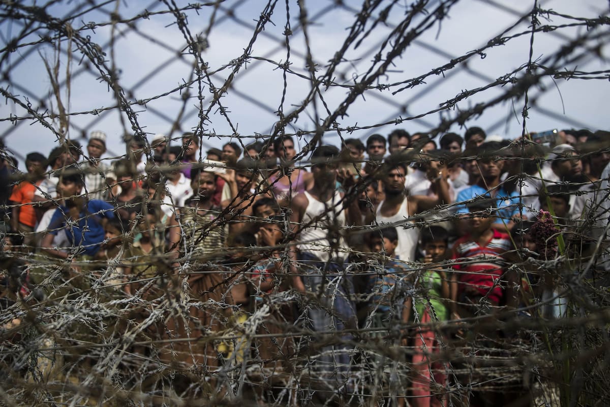En esta foto de archivo tomada el 25 de abril de 2018 en el distrito de Maungdaw, estado de Rakhine, Myanmar, se muestra a los refugiados rohingya reunidos detrás de una cerca de alambre de púas en un asentamiento temporal