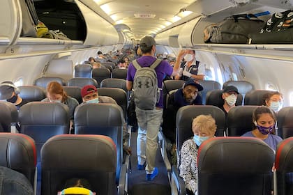 En esta foto de archivo tomada el 3 de mayo de 2020 los pasajeros, casi todos con mascarillas, suben a un vuelo de American Airlines con destino a Charlotte, en la ciudad de Nueva York.