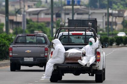 En esta foto de archivo tomada el 8 de abril de 2020, personas con trajes protectores acompañan a un ataúd en un camión cerca del hospital Los Ceibos en Guayaquil, Ecuador, en medio del nuevo brote de coronavirus