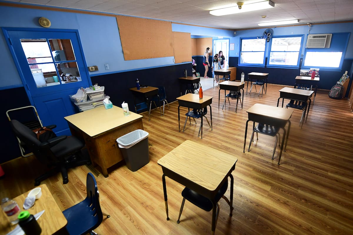 En esta foto de archivo tomada el 9 de julio de 2020, los niños con máscaras entran al aula con escritorios separados según las pautas de distanciamiento durante las sesiones de la escuela de verano en Monterey Park, California