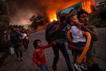 En esta foto de archivo tomada el 9 de septiembre de 2020 una familia de migrantes abandona el campamento de Moria después de que estallara un incendio en la isla de Lesbos