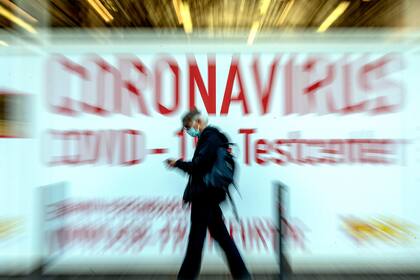 En esta foto del 25 de febrero de 2021, un hombre pasa frente al cartel de un centro de pruebas de COVID-19 en Fráncfort, Alemania.
(AP Foto/Michael Probst, file)