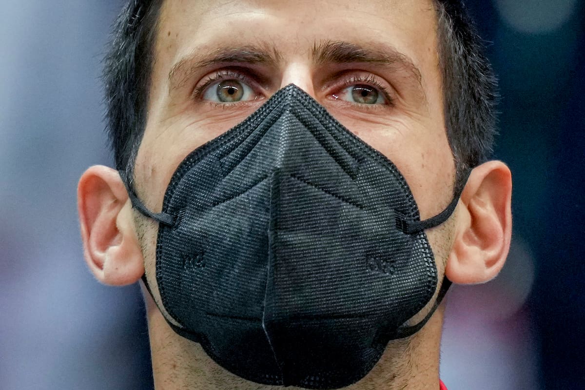 En esta foto del 26 de noviembre de 2021, el serbio Novak Djokovic usa una mascarilla durante la ceremonia de los himnos nacionales, antes de un partido de la Copa Davis entre su país y Austria, en Innsbruck. (AP Foto/Michael Probst)