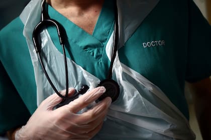 En esta foto del jueves 14 de mayo de 2020, un médico junior sostiene su estetoscopio durante una visita al paciente en la sala C22 en el Royal Blackburn Teaching Hospital, en Blackburn, Inglaterra, en medio de la pandemia de coronavirus.