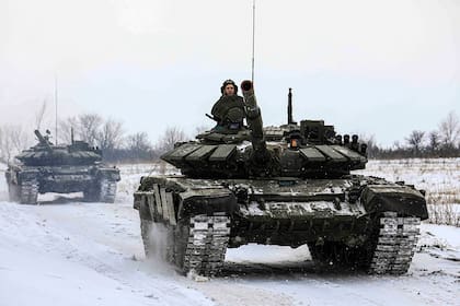 En esta foto distribuida por el Servicio de Prensa del Ministerio de Defensa ruso, tanques recorren un campo durante maniobras militares