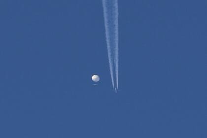 En esta foto proporcionada por Brian Branch, un gran globo se desplaza por encima de la zona de Kingstown, Carolina del Norte, mientras un avión pasa por debajo, dejando una estela a su paso. (Brian Branch vía AP)