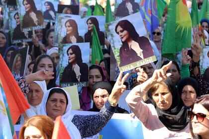 En esta foto proveída por la agencia kurda Hawar News Agency, mujeres kurdas llevan retratos de la iraní Mahsa Amini en una protesta por su asesinato en Irán, realizada en la ciudad iraquí de Qamishli el 26 de septiembre del 2022.