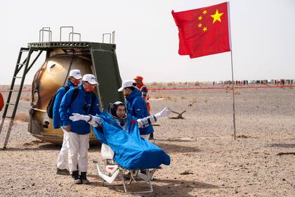 En esta foto publicada por la Agencia de Noticias Xinhua de China, el astronauta chino Ye Guangfu se sienta fuera de la cápsula de retorno de la misión espacial tripulada Shenzhou-13 después de aterrizar en el sitio de acoplamiento de Dongfeng  el sábado 16 de abril de 2022 en la Región Autónoma de Mongolia Interior del norte de China. (Cai Yang/Xinhua vía AP)