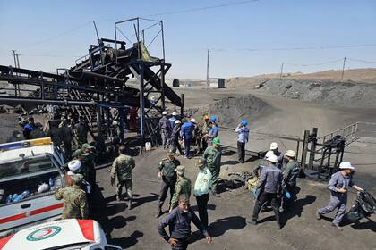 En esta foto publicada por la Sociedad de la Media Luna Roja Iraní, mineros y policías se ven junto a una mina de carbón donde una fuga de metano provocó una explosión el sábado en Tabas, unos 540 kilómetros (335 millas) al sureste de la capital, Teherán, Irán, el domingo 22 de septiembre de 2024. (Sociedad de la Media Luna Roja Iraní, via AP)