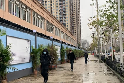 En esta foto tomada el 24 de noviembre de 2020, personas que usan mascarillas como medida preventiva contra el coronavirus caminan junto al mercado mayorista de mariscos de Huanan en Wuhan, en la provincia central china de Hubei