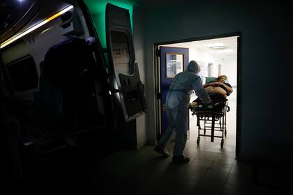 En esta fotografía de archivo del 1 de mayo de 2021 un trabajador de la salud traslada a una mujer sospechosa de tener Covid-19 en el Hospital Dr. Norberto Raúl Piacentini en Lomas de Zamora.