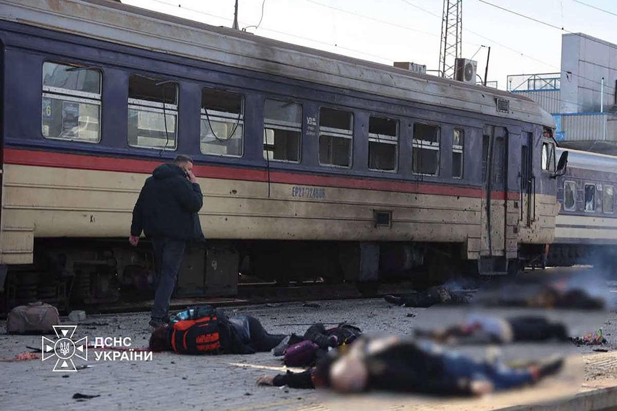 En esta fotografía facilitada por el Servicio de Emergencias de Ucrania el 29 de octubre de 2026, un hombre camina junto a los cuerpos de las víctimas que yacen al lado de un tren de pasajeros dañado tras un ataque aéreo contra la estación de tren de Dnipro
