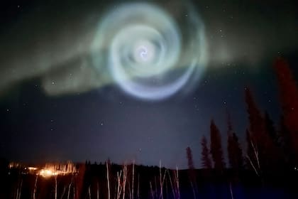 En esta fotografía proporcionada por Christopher Hayden, se muestra una espiral azul que parece una galaxia en medio de una aurora boreal en los cielos de Alaska cerca de Fairbanks, el sábado 15 de abril de 2023. (Christopher Hayden vía AP)