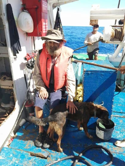 En esta fotografía proporcionada por Grupomar/Atun Tuny, el australiano Tim Shaddock permanece sentado con su perra Bella tras ser rescatado por un buque atunero mexicano en aguas internacionales del Pacífico, luego de que navegó a la deriva con Bella en su catamarán averiado durante tres meses. (Grupomar/Atun Tuny vía AP)
