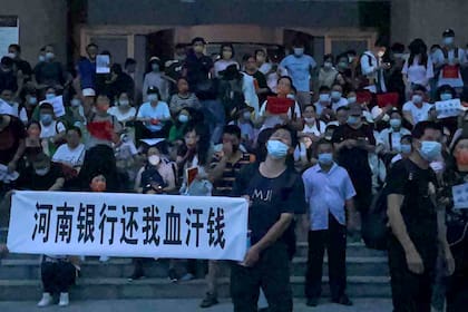 En esta fotografía publicada por Yang el domingo 10 de julio de 2022 se muestra a varias personas sosteniendo letreros y coreando consignas en una protesta a fuera de una sucursal del banco central de China en Zhengzhou en la provincia de Henan, en el centro de China. (AP Foto/Yang)