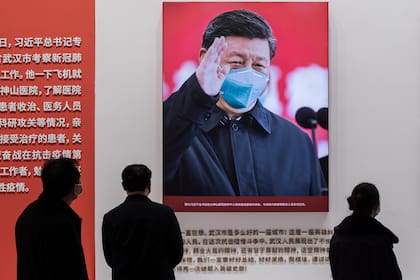 En esta fotografía tomada el 15 de enero de 2021, se muestra una imagen del presidente de China, Xi Jinping con una mascarilla facial, mientras la gente visita una exposición sobre la lucha de China contra el coronavirus en un centro de convenciones que anteriormente se utilizaba como hospital provi