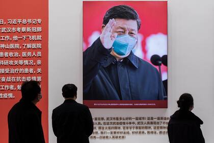 En esta fotografía tomada el 15 de enero de 2021, se muestra una imagen del presidente de China, Xi Jinping con una mascarilla facial, mientras la gente visita una exposición sobre la lucha de China contra el coronavirus en un centro de convenciones que anteriormente se utilizaba como hospital provi