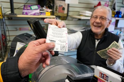 En esta imagen de archivo, Dot Skoko, propietario de la tienda Dot's Dollar More or Less en Mt. Lebanon, Pensilvania, entrega un boleto de la lotería Mega Millions