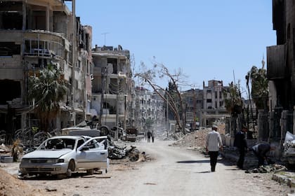 En esta imagen de archivo, sitios caminan por la destruida localidad de Douma, el escenario de un presunto ataque con armas químicas, cerca de Damasco, Siria, el 16 de abril de 2018. (AP Foto/Hassan Ammar, archivo)