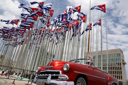 En esta imagen de archivo, un auto descapotable clásico estadounidense pasa junto a la embajada de Estados Unidos mientras las banderas cubanas ondean en la Tribuna Antiimperialista, en el Malecón, en La Habana, Cuba, el 26 de julio de 2015
