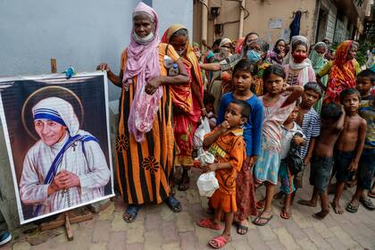 En esta imagen de archivo, un grupo de personas sin hogar se reúne junto a un retrato de Santa Teresa, la fundadora de Misioneras de la Caridad, para recibir comida, en el exterior de su sede en Calcuta, India, el 26 de agosto de 2021. (AP Foto/Bikas Das, archivo)