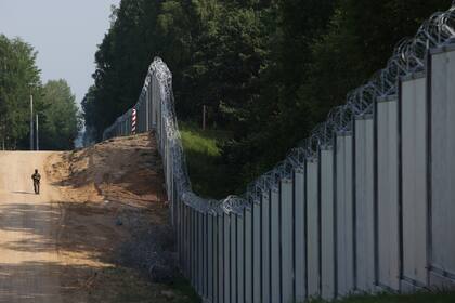 En esta imagen de archivo, un guarda fronterizo polaco patrulla por las inmediaciones de una cerca de metal en la frontera entre Polonia y Bielorrusia, cerca de Kuznice, Polonia, el 30 de junio de 2022. (AP Foto/Michal Dyjuk, archivo)