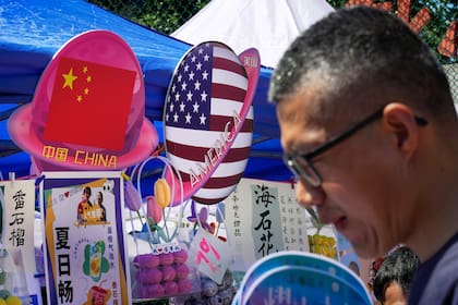 En esta imagen de archivo, un hombre pasa por delante de un puesto de venta de comida y bebida con banderas de China y Estados Unidos, durante una fiesta de primavera en Beijing, el 13 de mayo de 2023. (AP Foto/Andy Wong, archivo)