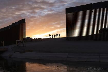 En esta imagen del 10 de junio de 2021, un par de familias de inmigrantes brasileños cruzan por una apertura en el muro fronterizo desde México hacia Yuma, Arizona, con el fin de solicitar asilo. (AP Foto/Eugene Garcia, archivo)
