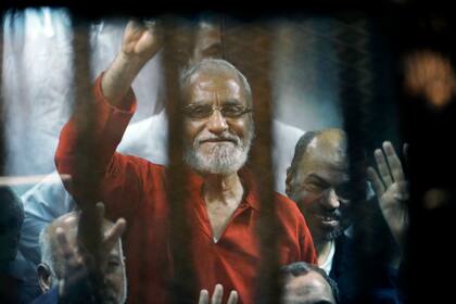 En esta imagen del 16 de mayo de 2015, el líder espiritual de la Hermandad Musulmana, Mohamed Badie, saluda desde la celda de acusados en un tribunal improvisado en la academia nacional de policía, en El Cairo. (AP Foto/Ahmed Omar, archivo)