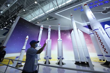 En esta imagen del 29 de septiembre de 2021, un visitante toma fotos de réplicas de cohetes espaciales de lanzamiento en la Feria Aérea China de 2021 en Zhuhai, en la provincia sureña china de Guangdong.