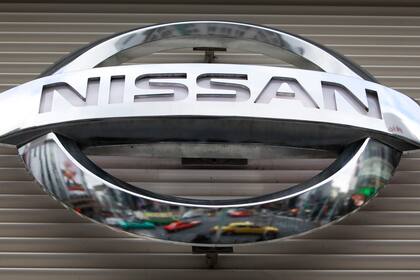 En esta imagen del 8 de febrero de 2012, se ven vehículos reflejados en un logotipo de Nissan Motors Co. en una sala de exhibiciones en el distrito comercial Ginza, de Tokio.  (AP Foto/Shizuo Kambayashi, Archivo)