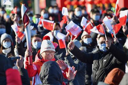 En esta imagen, distribuida por la agencia noticiosa oficial china Xinhua, Luo Zhihuan corre entre la gente portando la antorcha olímpica al inicio del recorrido de la llama antes de los Juegos Olímpicos de Invierno de Beijing 2022, en el parque olímpico de Beijing, el 2 de febrero de 2022. (Chen Zhonghao/Xinhua vía AP)