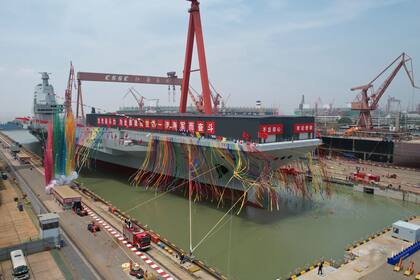 En esta imagen distribuida por la agencia noticiosa Xinhua, humo y cintas de colores conmemoran la botadura del tercer portaaviones de China, bautizado como Fujian, en Shanghái, el 17 de junio de 2022. (Li Gang/Xinhua vía AP)
