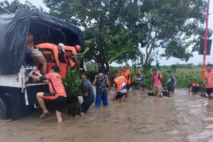 En esta imagen, distribuida por la Guardia Costera de Filipinas, rescatistas ayudan a residentes a trasladarse a un lugar seguro en Tuguegarao, en la provincia de Cagayan, en el norte de Filipinas, el 23 de agosto de 2022 tras el paso de una tormenta tropical. (Guardia Costera de Filipina vía AP)