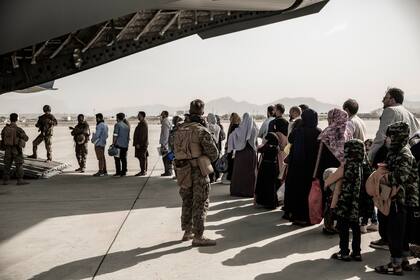 En esta imagen distribuida por los Marines, evacuados aguardan en fila para abordar un Boeing C-17 Globemaster III durante una evacuación en el Aeropuerto Internacional Hamid Karzai de Kabul, Afganistán, 30 de agosto de 2021. (Staff Sgt. Victor Mancilla/U.S. Marine Corps via AP)