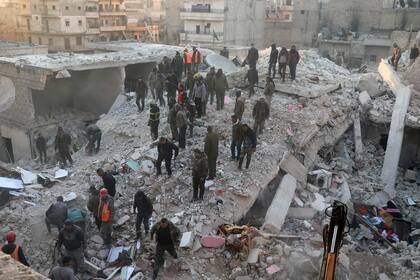 En esta imagen proporcionada por la Agencia de Noticias Hawar, un medio kurdo, personal de defensa civil y civiles trabajan en los restos de un edificio destruido en el vecindario de Sheikh Maksoud en Alepo, Siria, el domingo 22 de enero de 2023. (Agencia de Noticias Hawar via AP)