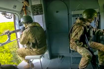 En esta imagen publicada por el servicio de prensa del Ministerio ruso de Defensa el sábado 28 de mayo de 2022, soldados rusos controlan la situación a bordo de un helicóptero Mi-8 de la fuerza aérea rusa, durante una misión en un lugar no revelado en Ucrania. (Servicio de prensa del Ministerio ruso de Defensa via AP)