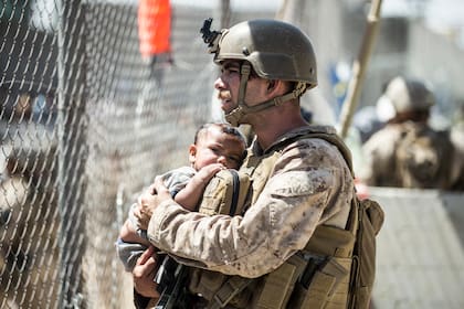 En esta imagen suministrada por el Cuerpo de Infantería de Marina de EEUU, un efectivo carga a un bebé durante las operaciones de evacuación en el Aeropuerto Internacional Hamid Karzai en Kabul, Afganistán