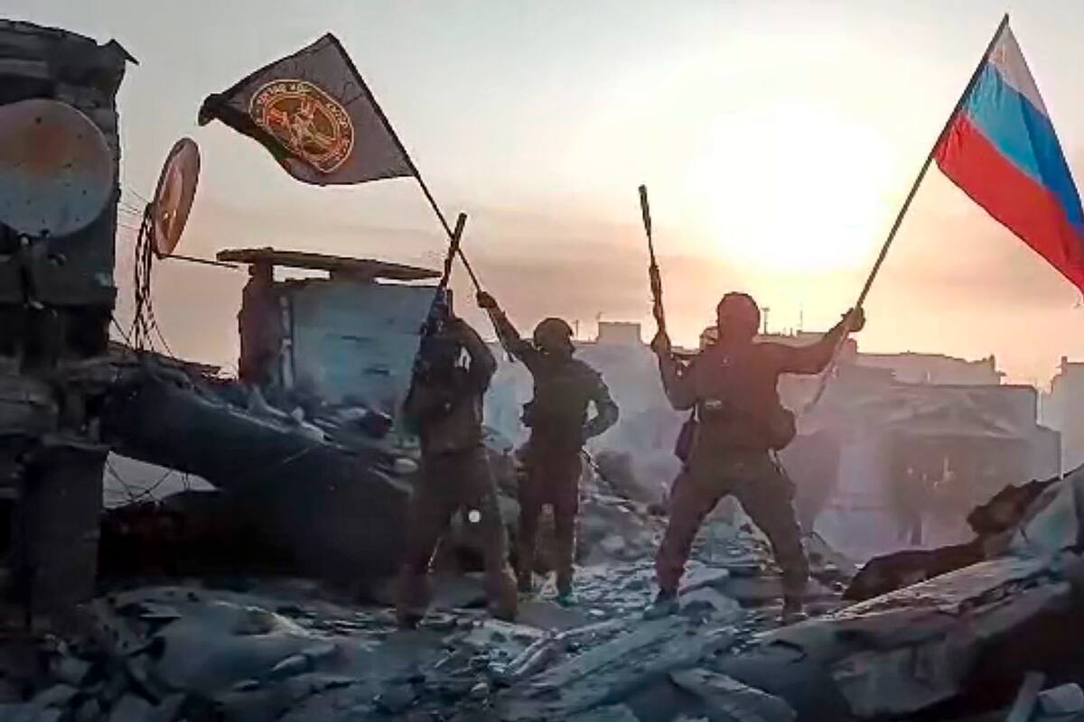 En esta imagen tomada de un video difundido por el Servicio de Prensa Prigozhin, integrantes de la compañía militar Grupo Wagner de Yevgeny Prigozhin ondean una bandera rusa y otra del Grupo Wagner en una estructura dañada en Bakhmut, Ucrania. (Servicio de Prensa Prigozhin vía AP)